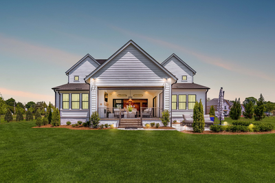 White craftsman-style home with three gabled roofs and covered outdoor living area at dusk