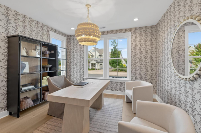 Home office with modern desk, patterned wallpaper, and gold tiered chandelier
