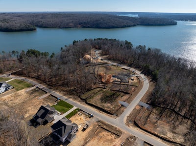 Aerial view of lakefront residential development with homes under construction on wooded peninsula