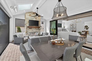 Covered outdoor patio with stone fireplace, wicker furniture, and ceiling fan