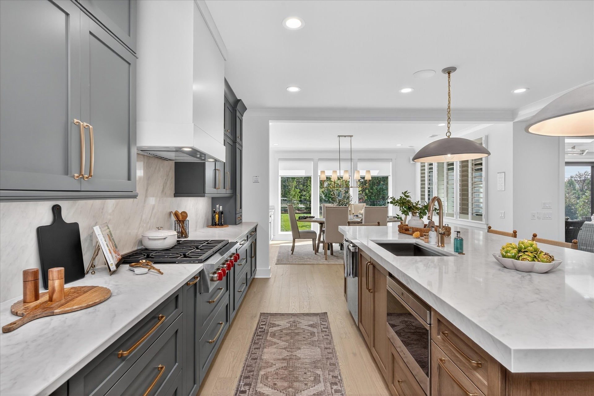 Modern kitchen with gray and wood cabinets, white countertops, and gold fixtures