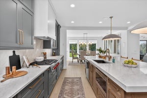 Modern kitchen with gray and wood cabinets, white countertops, and gold fixtures