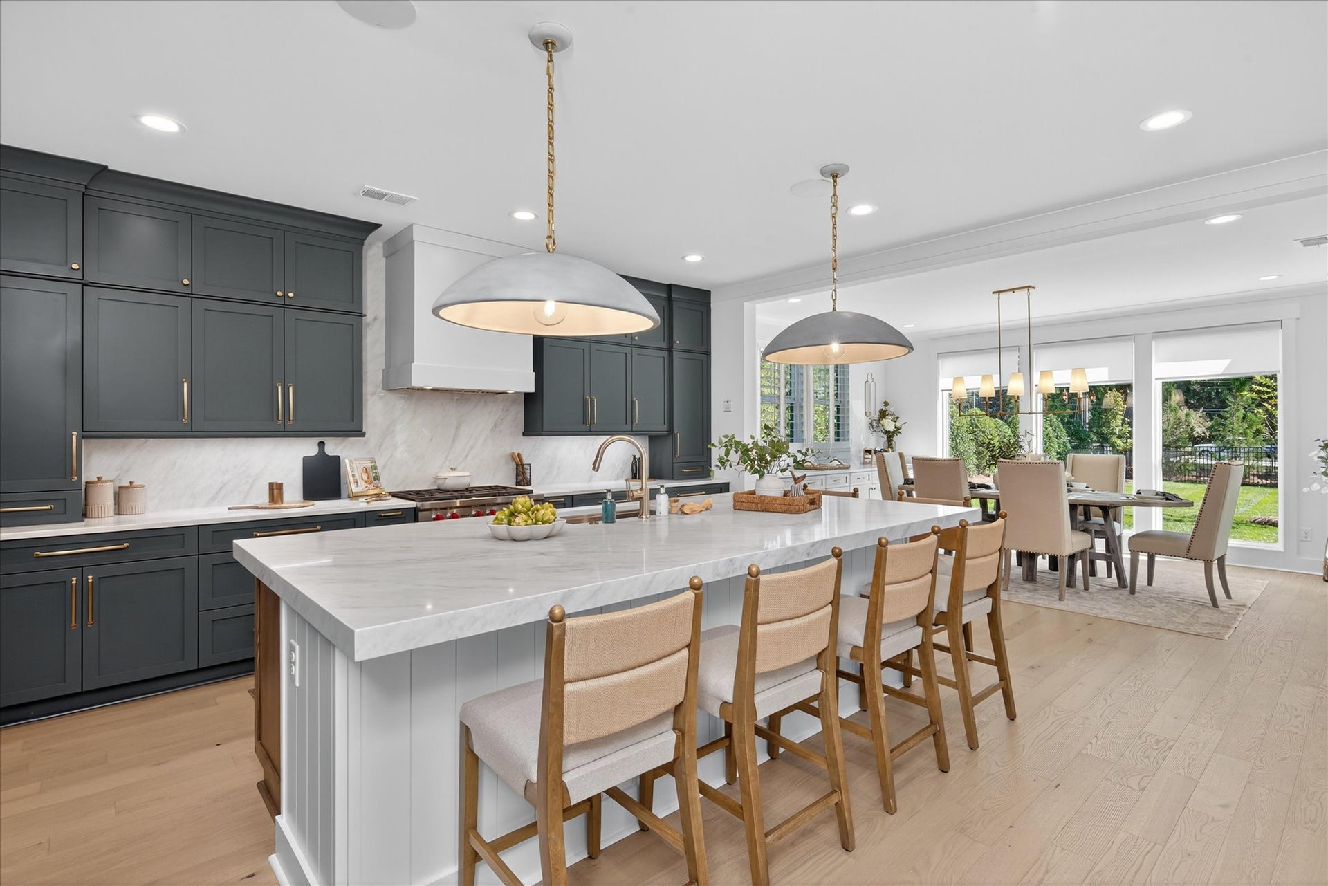 Open-concept kitchen and dining area with gray cabinets, white island, and pendant lighting