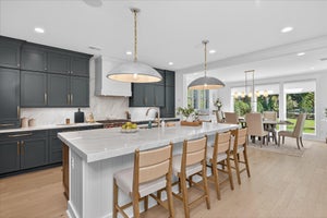 Open-concept kitchen and dining area with gray cabinets, white island, and pendant lighting