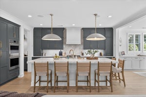 Modern kitchen with gray and white cabinets, large island with seating, and pendant lighting