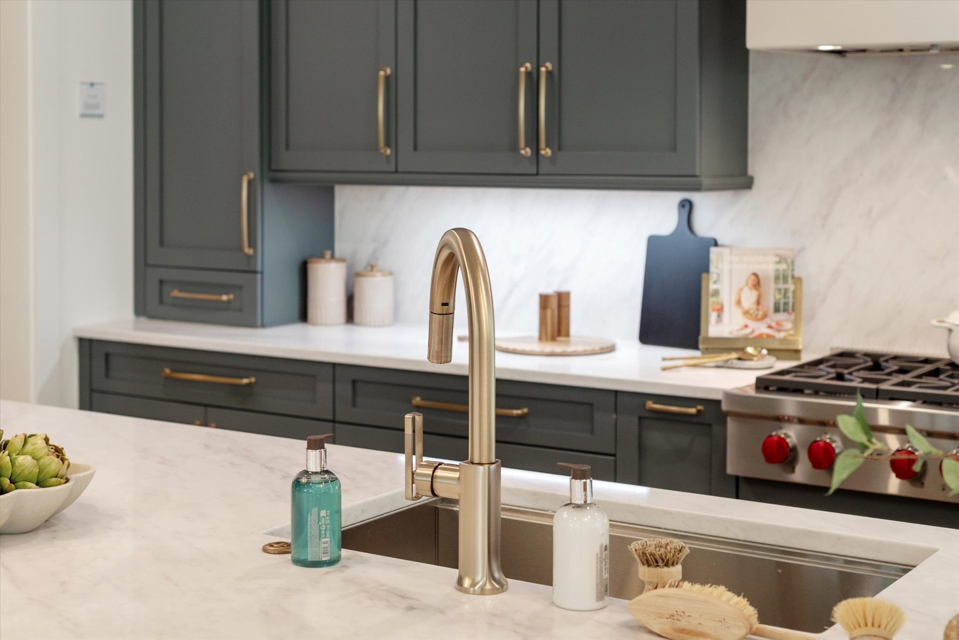Modern kitchen with gray cabinets, white countertops, gold hardware, and stainless steel appliances