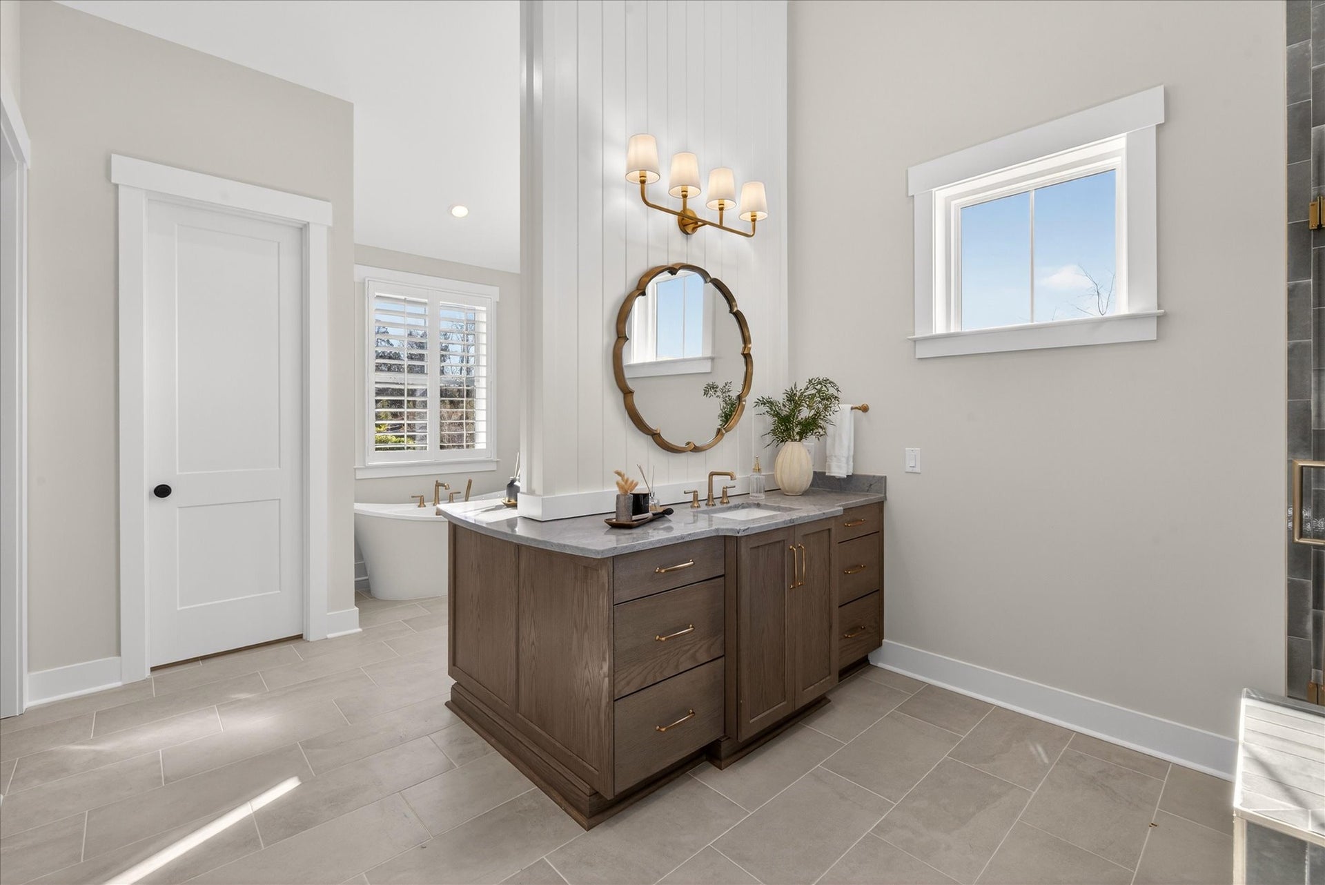 Master bathroom with dark wood double vanity, round mirror, and tile flooring