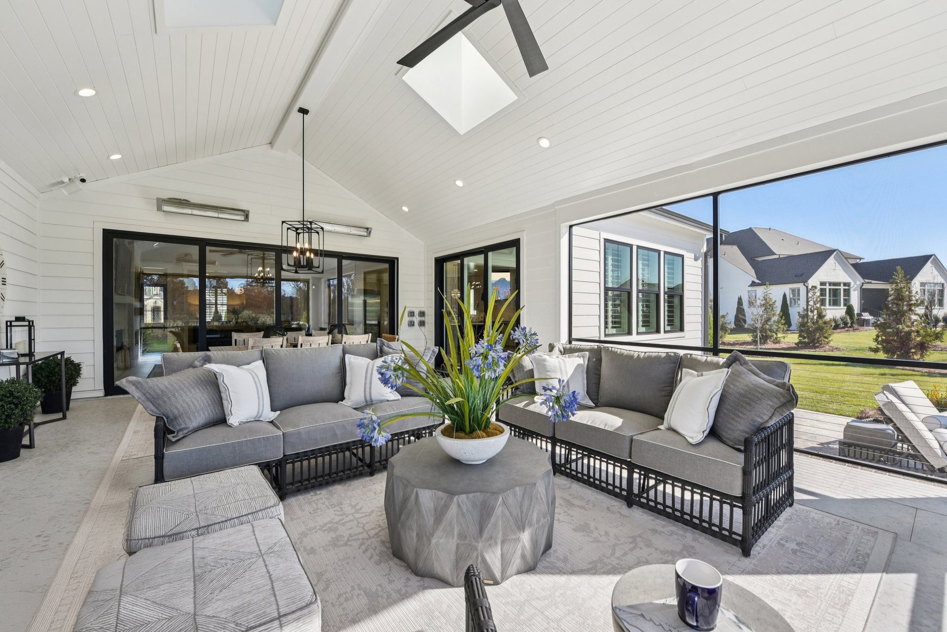 Covered outdoor patio with vaulted ceiling, skylight, gray furniture, and black-framed glass doors