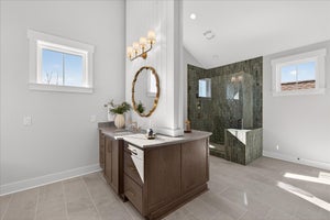 Modern bathroom with wood vanity, round mirror, and glass-enclosed shower with green tile