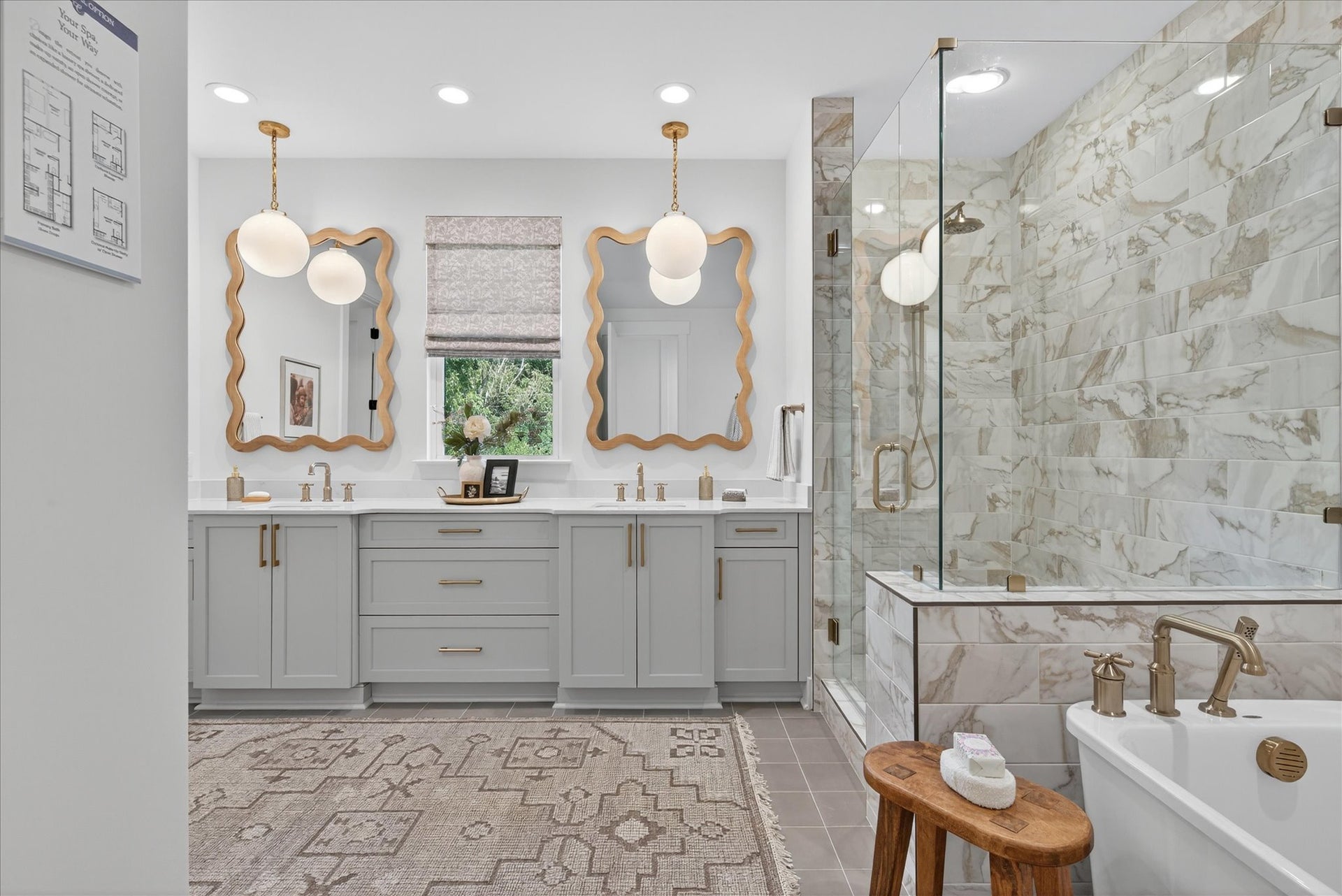 Master bathroom with gray double vanity, gold mirrors, marble shower, and soaking tub