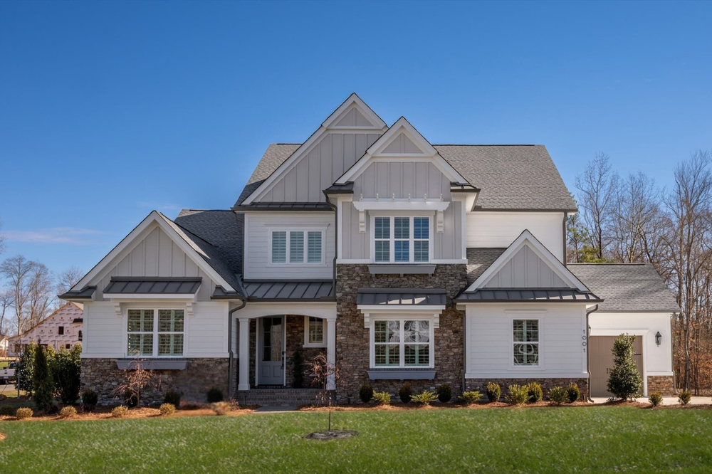 Two-story home with white and gray siding, stone accents, and multiple gabled rooflines