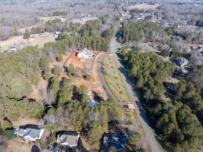 Aerial view of suburban neighborhood with homes along tree-lined streets and landscaped median