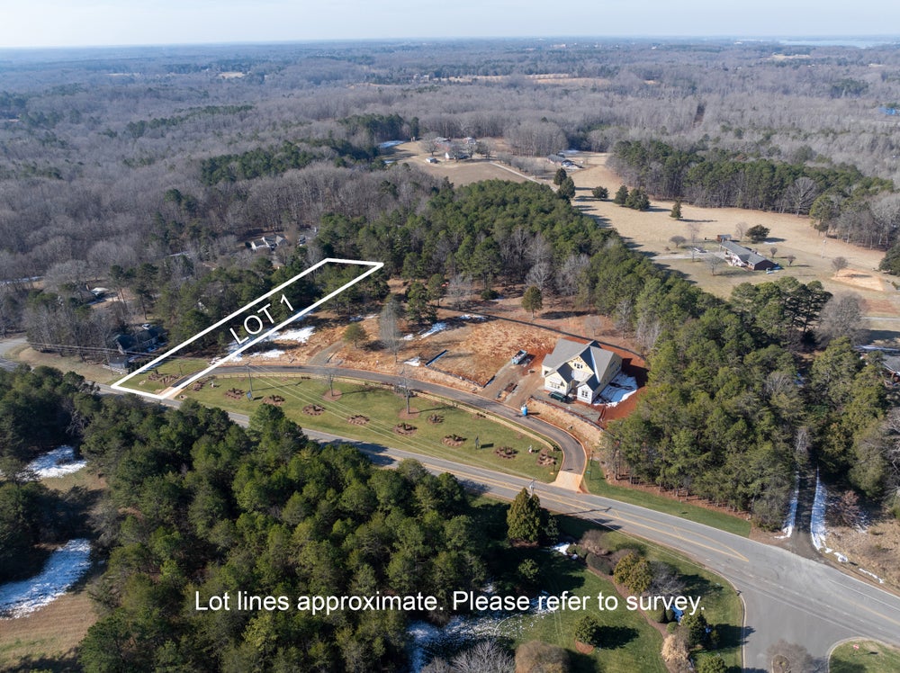 Aerial view of wooded building lot marked as Lot 1 in residential subdivision