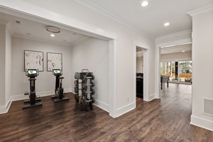 Home gym with exercise equipment, hardwood floors, and white walls