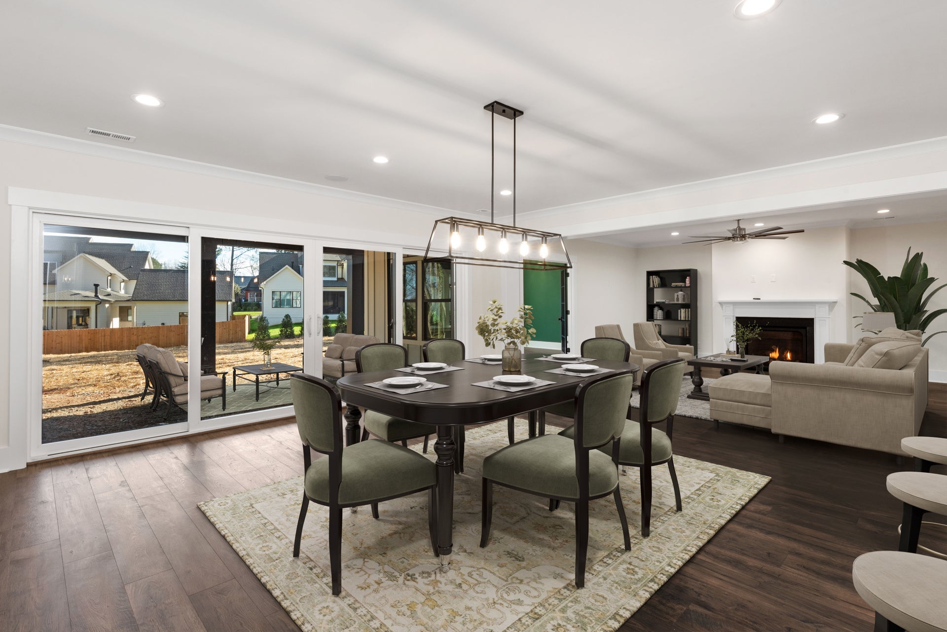 Open-concept dining and living room with dark wood floors, sliding glass doors, and fireplace