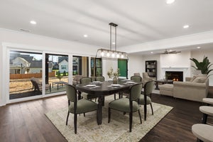 Open-concept dining and living room with dark wood floors, sliding glass doors, and fireplace