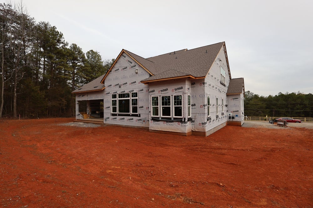 Single-story home under construction with house wrap and attached garage