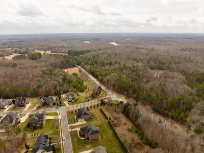 Aerial view of suburban neighborhood with homes surrounded by wooded rural landscape