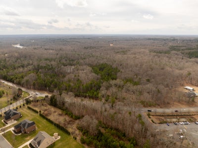 Aerial view of wooded land parcel with nearby residential homes and highway access