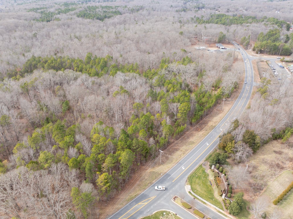 Aerial view of curved road through wooded area with undeveloped land on both sides