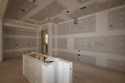 Kitchen under construction with drywall installation and island framing in progress