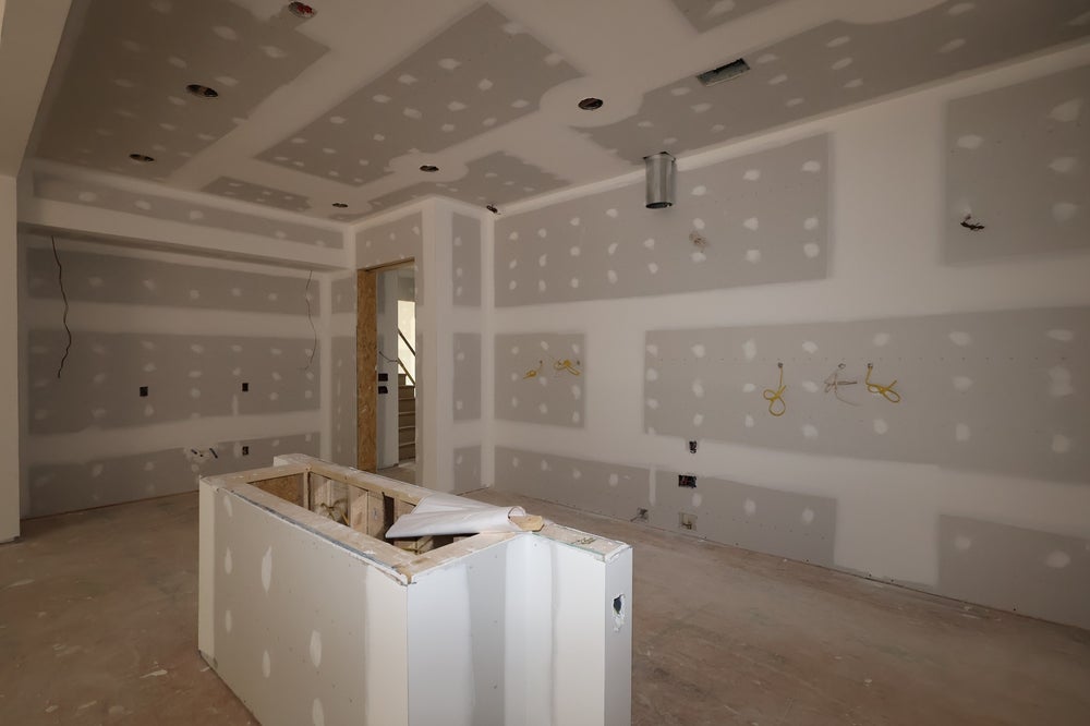 Kitchen under construction with drywall installation and island framing in progress