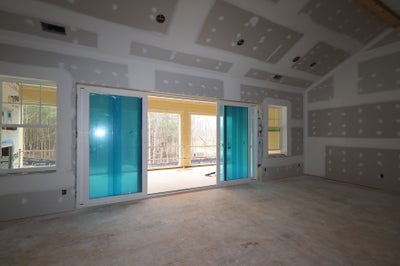 Unfinished room with drywall walls, coffered ceiling, and sliding glass doors to deck