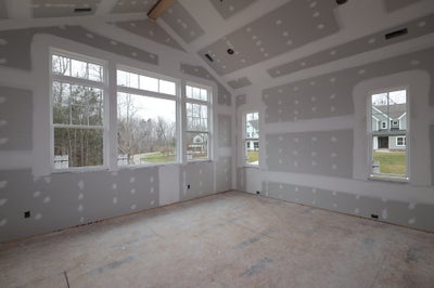 Empty room under construction with large windows and unfinished drywall walls