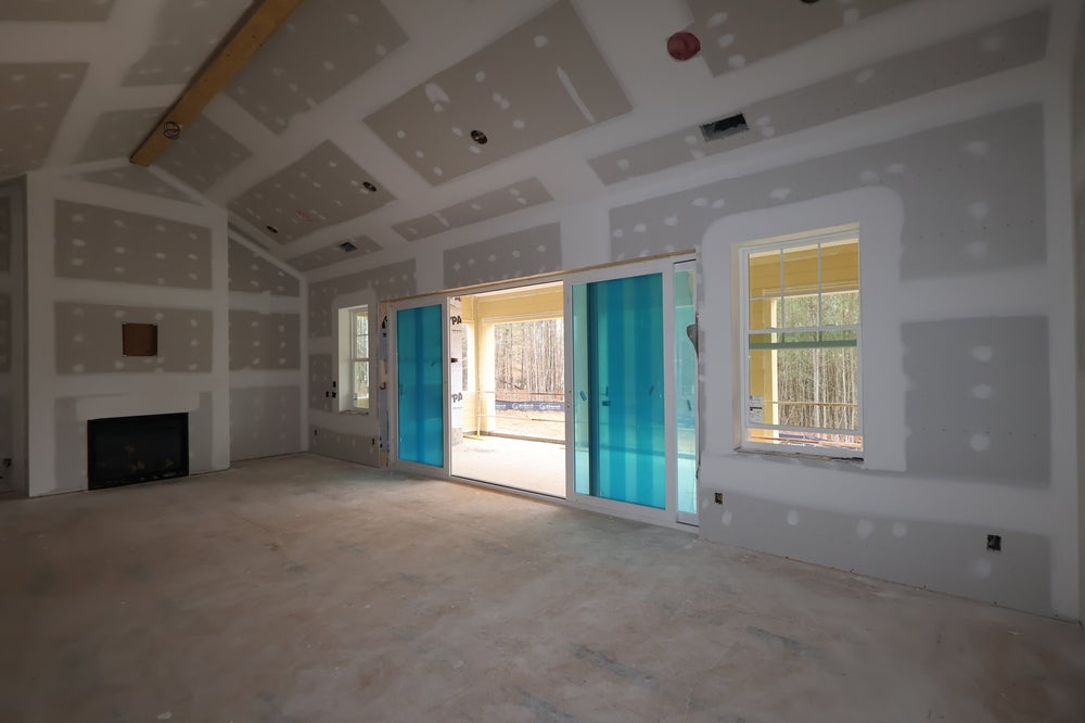 Living room under construction with coffered ceiling, fireplace, and glass doors to patio