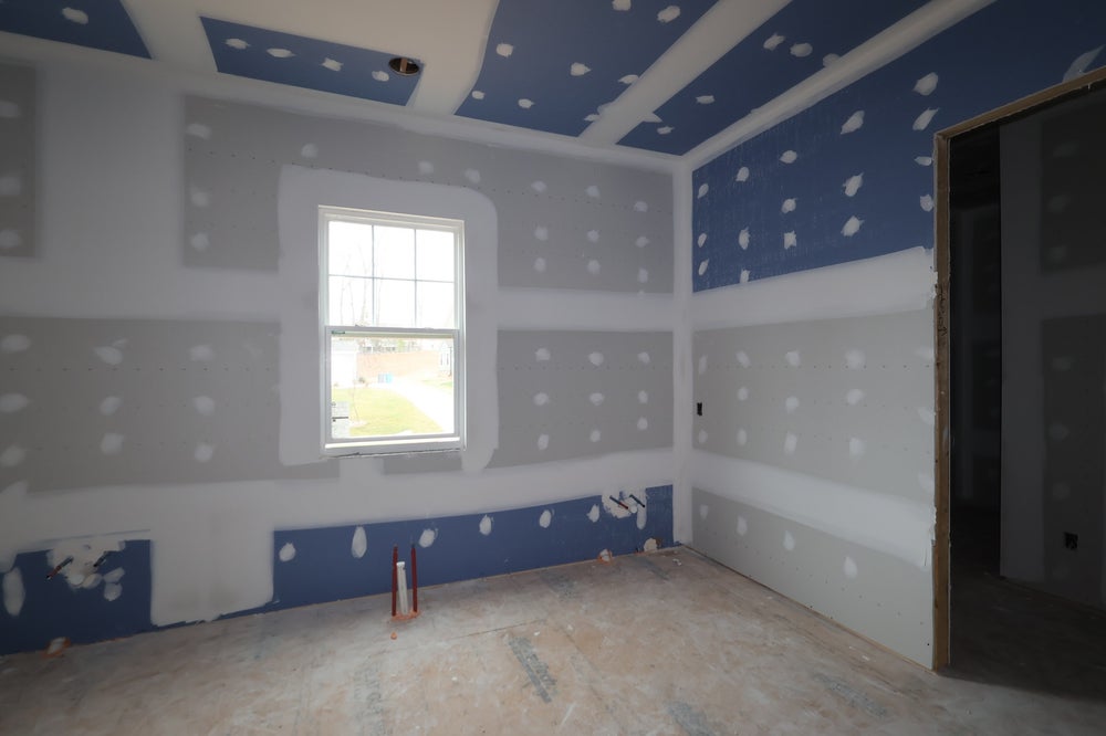 Empty room under construction with blue painted ceiling and unfinished drywall walls