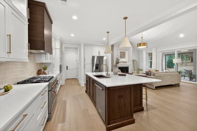 Open-concept kitchen with white cabinets, dark wood island, and light hardwood floors