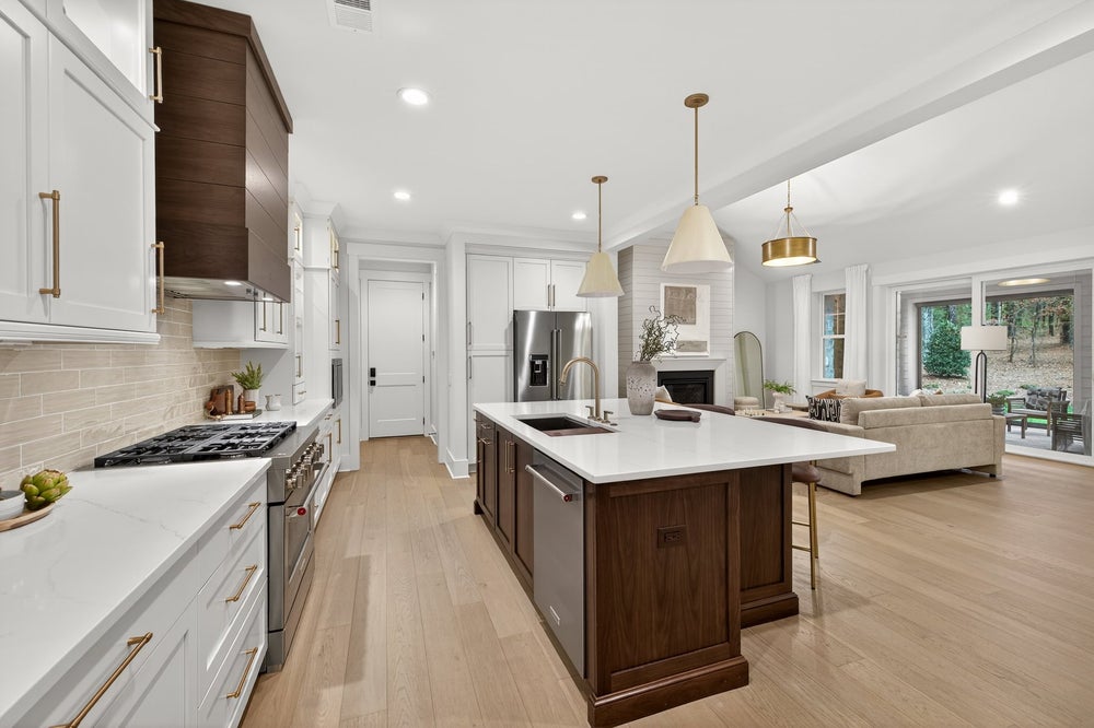 Open-concept kitchen with white cabinets, dark wood island, and light hardwood floors