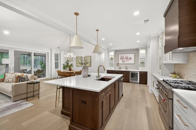 Open-concept kitchen with dark wood island, white countertops, and pendant lighting overlooking living area