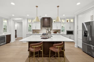 Modern kitchen with white cabinets, dark wood island, quartz countertops, and stainless steel appliances