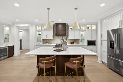 Modern kitchen with white cabinets, dark wood island, quartz countertops, and stainless steel appliances