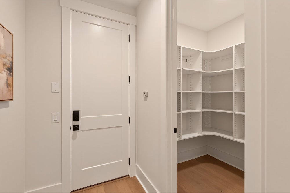 Walk-in closet with white built-in shelving and hardwood floors