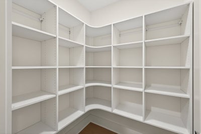 Walk-in closet with white built-in shelving and adjustable storage compartments