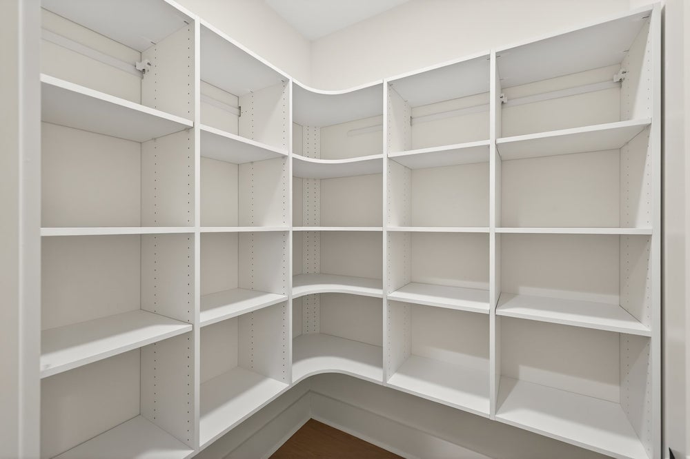 Walk-in closet with white built-in shelving and adjustable storage compartments
