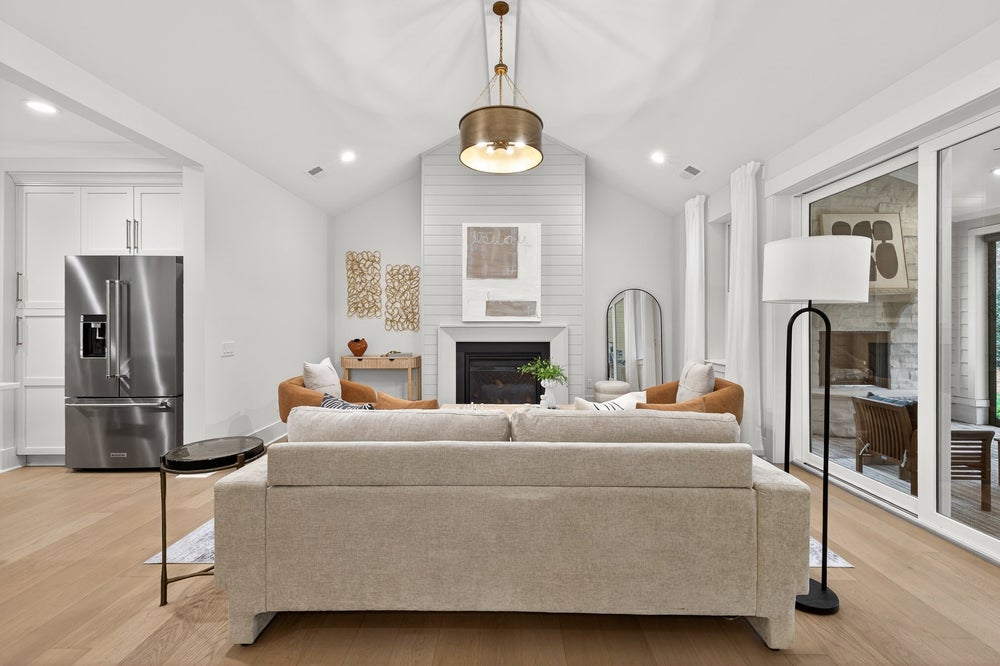 Open-concept living room with vaulted ceiling, fireplace, and view to kitchen