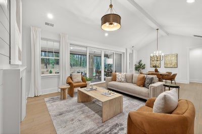 Open concept living and dining room with vaulted ceiling, light wood floors, and patio access