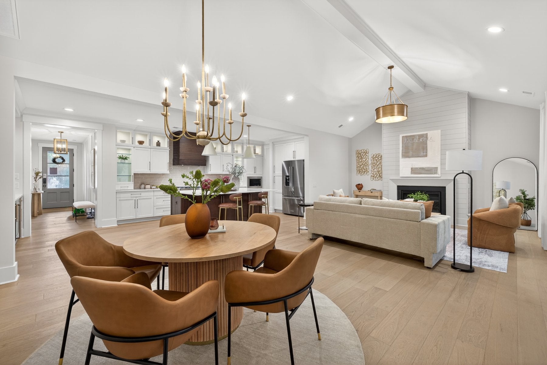 Open-concept living space with dining area, kitchen, and living room with vaulted ceiling and hardwood floors