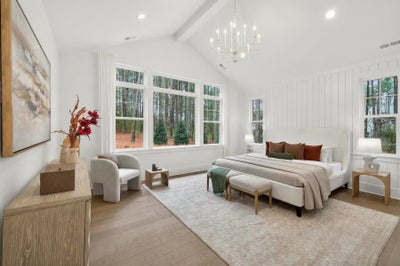Master bedroom with vaulted ceiling, white shiplap walls, chandelier, and large windows overlooking woods