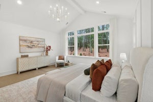Master bedroom with vaulted ceiling, chandelier, and large windows overlooking wooded area