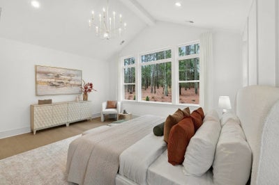 Master bedroom with vaulted ceiling, chandelier, and large windows overlooking wooded area