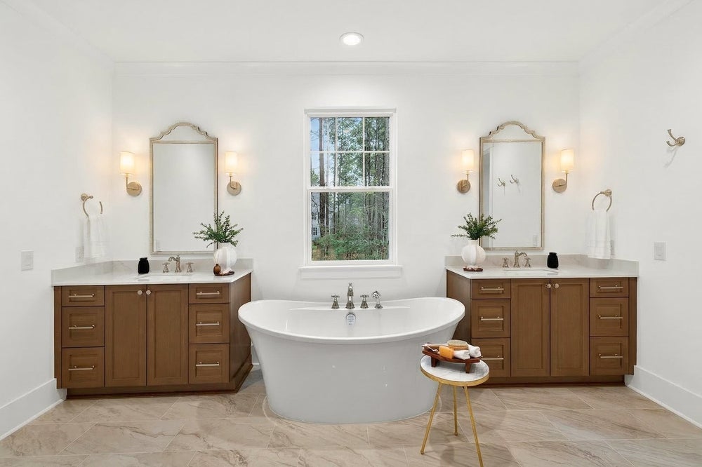 Master bathroom with freestanding tub, dual vanities with wood cabinets, and white countertops