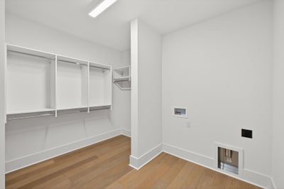 Walk-in closet with built-in shelving, hanging rods, and hardwood floors