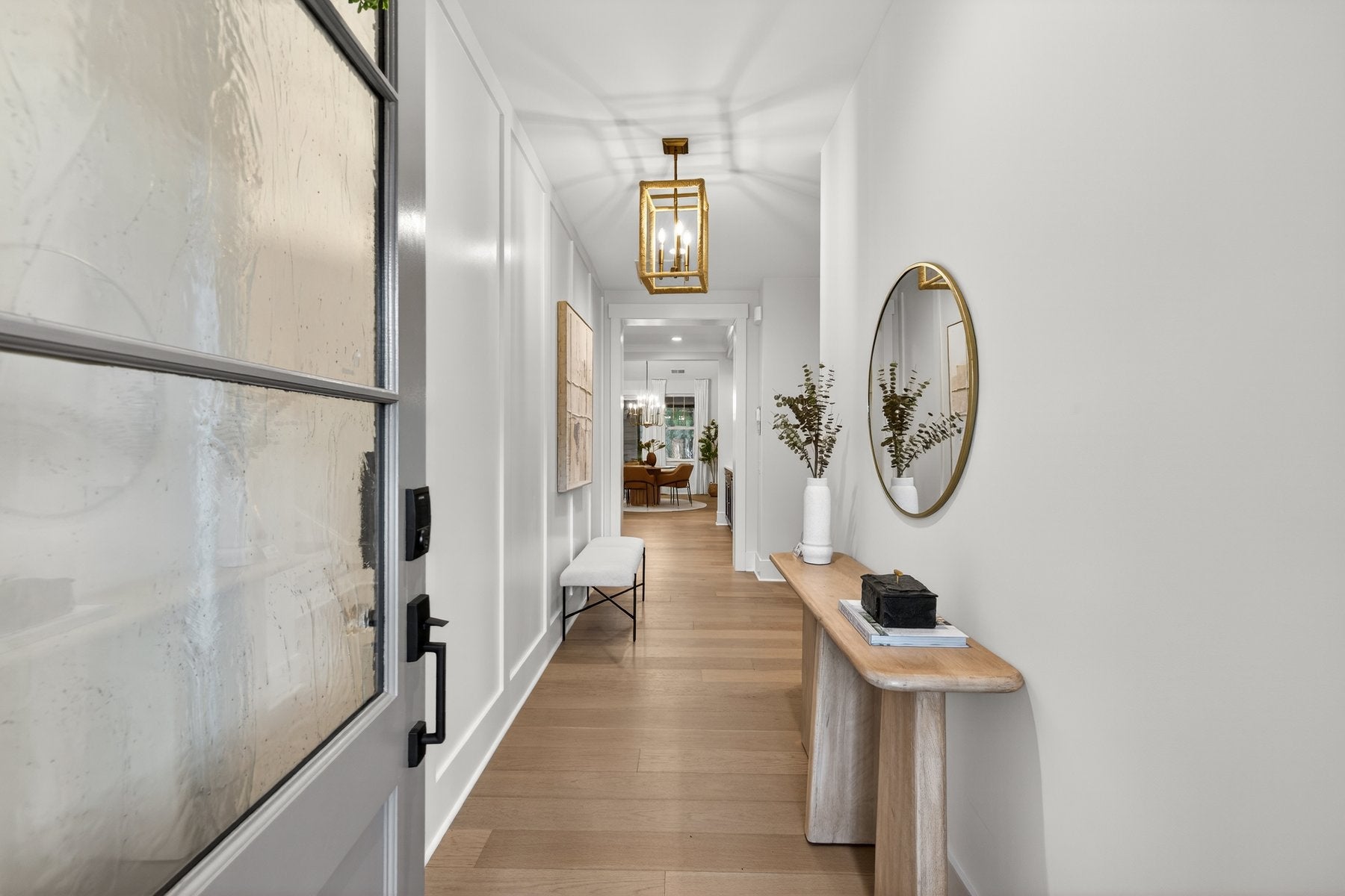 Bright entryway hallway with hardwood floors, console table, and gold pendant light