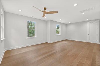Empty room with light gray walls, hardwood floors, and ceiling fan
