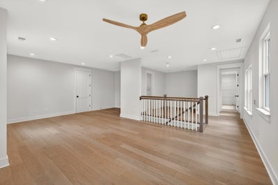 Upper floor landing with wood ceiling fan, staircase railing, and hardwood floors