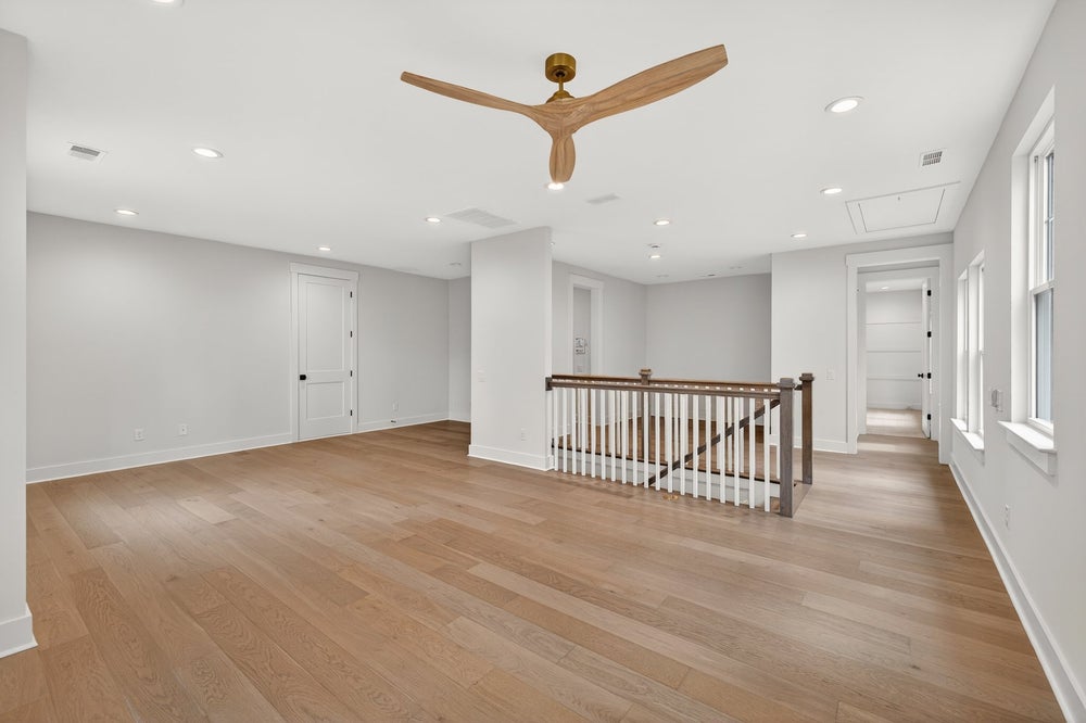 Upper floor landing with wood ceiling fan, staircase railing, and hardwood floors